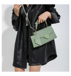 Detail of mint green crocodile embossed handbag with scrunchie handle and gold metal clasp