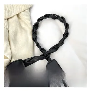 Detail of twisted woven black faux leather strap on a denim shoulder bag for women
