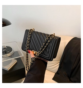 Close-up of black chevron quilted crossbody bag featuring a gold chain strap and square push lock