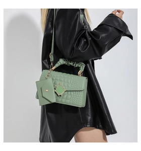 Detail of sage green croc-embossed crossbody bag with pleated handle and mini pouch