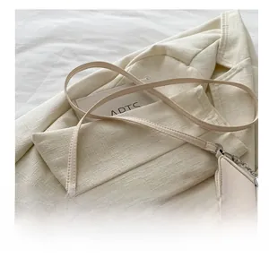 Dettaglio dell'elegante borsa a tracolla in pelle beige con cuciture fini e fibbie argento