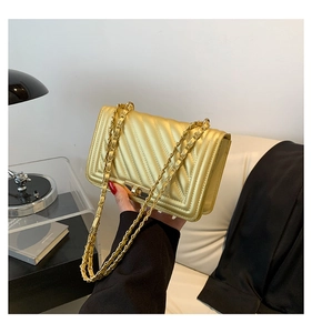 Detail of gold chain shoulder bag featuring V-shaped quilting and a sleek metal turn-lock