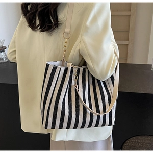 Detail of striped tote bag with leather strap and gold chain link in warm lighting
