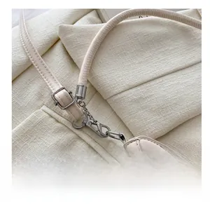 Dettaglio del gancio metallico argento e tracolla regolabile sulla borsa bianco avorio