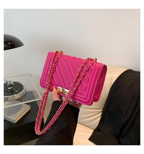 Detail of bright pink quilted crossbody bag with gold lock and chain strap