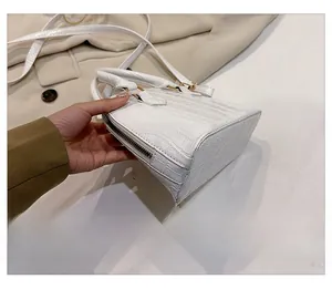 Detail of white crocodile pattern shell bag with side zipper and gold hardware