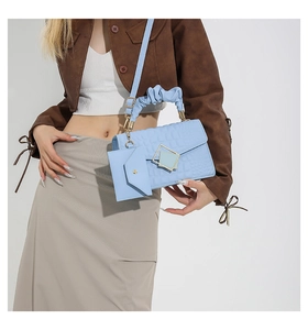 Detail of light blue crocodile embossed handbag with pleated handle and gold lock