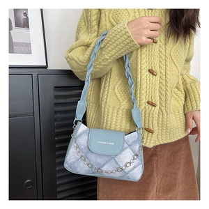 Detail of light blue shoulder bag featuring textured fabric and floral silver chain