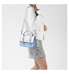 Detail of blue and white contrast shoulder bag with gold hardware on white blazer