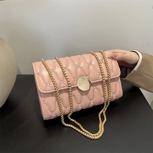 Sac bandoulière rose matelassé avec chaîne dorée, tenu à la main pour l'échelle