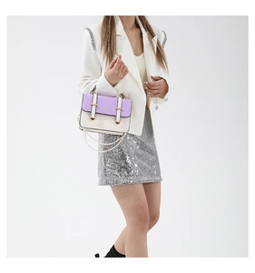 Detail of color-block crossbody bag in purple and cream worn by a model in a studio