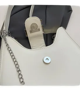 Close-up of a white leather bag featuring a polished silver magnetic clasp and metal chain