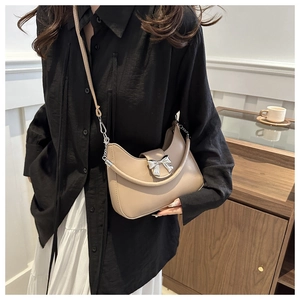 Vista dettagliata della borsa hobo beige con fiocco argento e tracolla regolabile