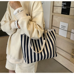 Close-up of black and white striped canvas tote bag with leather strap and gold chain