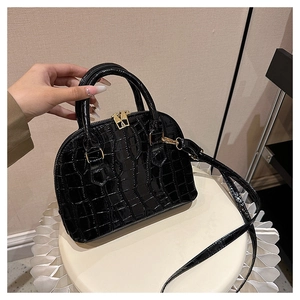 Detailed close-up of glossy black crocodile pattern texture and gold hardware on handbag