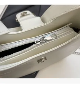 Detail view of smooth silver metal zipper and interior lining of white PU shoulder bag