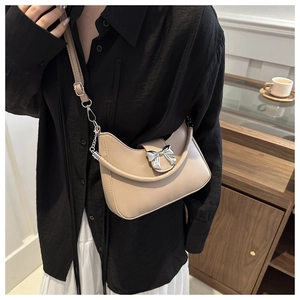 Dettaglio borsa a mezzaluna beige con fiocco in metallo argento e tracolla regolabile