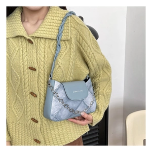 Detail of light blue denim texture bag with braided strap and floral metal chain
