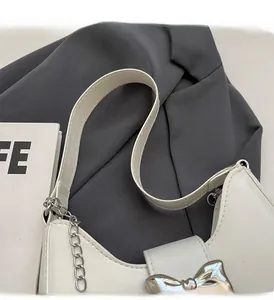 Detail of white moon bag featuring silver metal bow and decorative chain handle