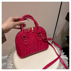 Detail of rose red shell handbag featuring embossed crocodile texture and gold zippers