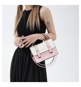 Detail of a pink and white color-block crossbody bag with gold hardware and logo