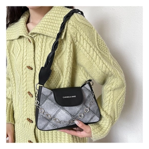 Detail of denim quilted shoulder bag with leather flap and floral silver chain strap