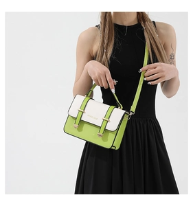 Detail shot of two-tone green and white flap crossbody bag worn with a black dress