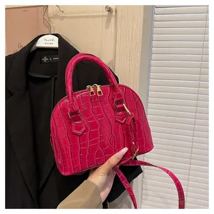 Detailed view of magenta crocodile pattern shell bag with gold hardware and shoulder strap