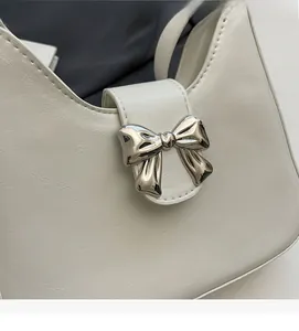 Detailed macro view of white leather texture and silver metal bow buckle on shoulder bag