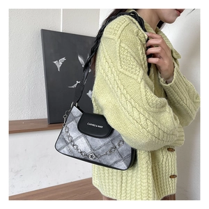 Detail of silver metallic shoulder bag with black leather flap and floral chain strap