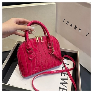 Macro detail of glossy pink crocodile embossed mini bag with gold hardware and handles
