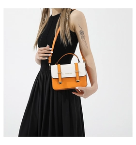 Detail of a bright orange and cream color-block crossbody bag with metal buckles