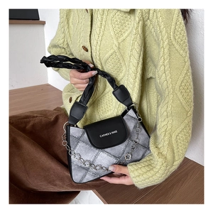 Detail of grey plaid underarm bag with black leather flap and metal flower chain