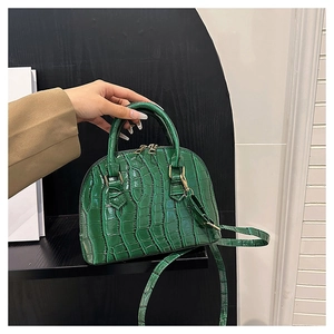 Detail of dark green crocodile texture shell bag with golden zipper and adjustable strap