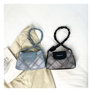 Detail of plaid denim shoulder bag with woven handle and floral metal chain accessory