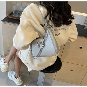 Close-up of metallic silver shoulder bag with bow buckle and chain strap on a model