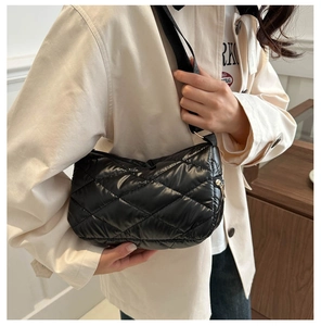 Mannequin portant un sac bandoulière matelassé noir brillant avec fermeture éclair dorée