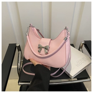 Dettaglio borsa a mezzaluna rosa con chiusura a fiocco argento e tracolla a catena