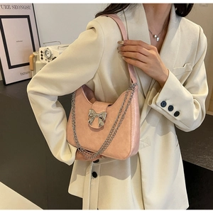 Detail of pink shoulder bag with textured leather and a silver metal bow buckle