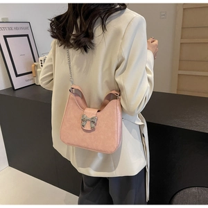 Pink matte leather shoulder bag with a silver metal bow and chain strap on a model