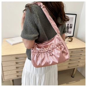 Detail of pink satin pleated shoulder bag with decorative bow and ruched strap