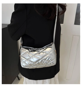 Détail du sac bandoulière argenté matelassé avec texture métallique porté par modèle