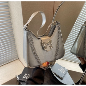 Detail of silver metallic handbag featuring bow buckle and sleek chain strap texture