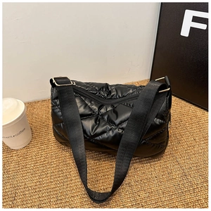 Détail du sac matelassé noir avec bandoulière large et finitions dorées chic