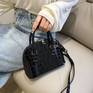 Chic black crocodile embossed shell bag with gold hardware and a detachable strap