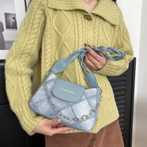 Chic light blue and silver shoulder bag with floral chain and woven handle on a model