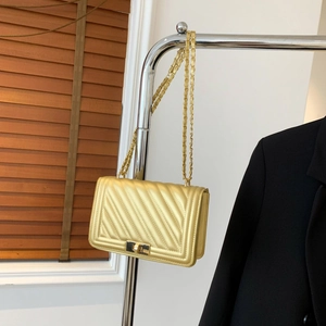 Elegant gold quilted crossbody bag with metallic finish and chain strap on display