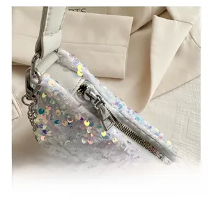 Detailed close-up of a white sequin handbag featuring a smooth metal zipper and leather strap