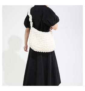 Close-up of white bubble texture fabric on a large capacity pleated crossbody bag