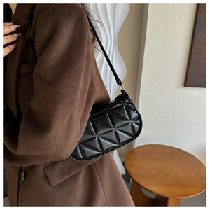 Dettaglio borsa sottobraccio in PU nero con motivo geometrico 3D indossata da una modella